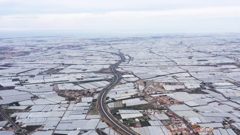 Road-aerial-view-sea-of-plastic-Spain-endless-fields-of-greenhouses-cloudy-day